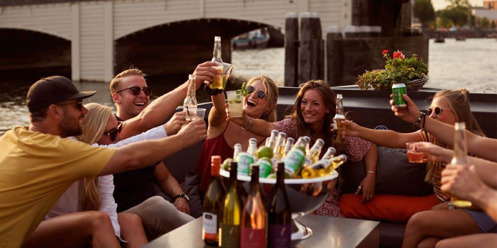 Gezelschap aan boord bij zonsondergang met snacks en drankjes